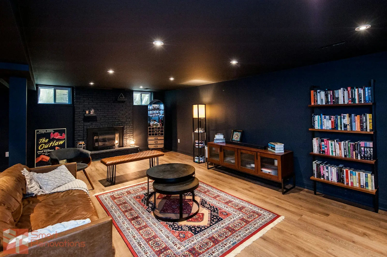 A finished basement with a fireplace, bookshelves and deep navy walls